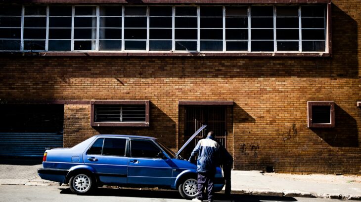 two men fixing up blue car